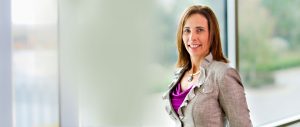 Erica Lewis wearing a gray suit and purple shirt