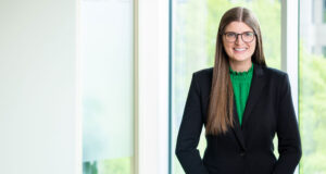 Ellen Koscielniak in front of a window wearing a black blazer over a green blouse.